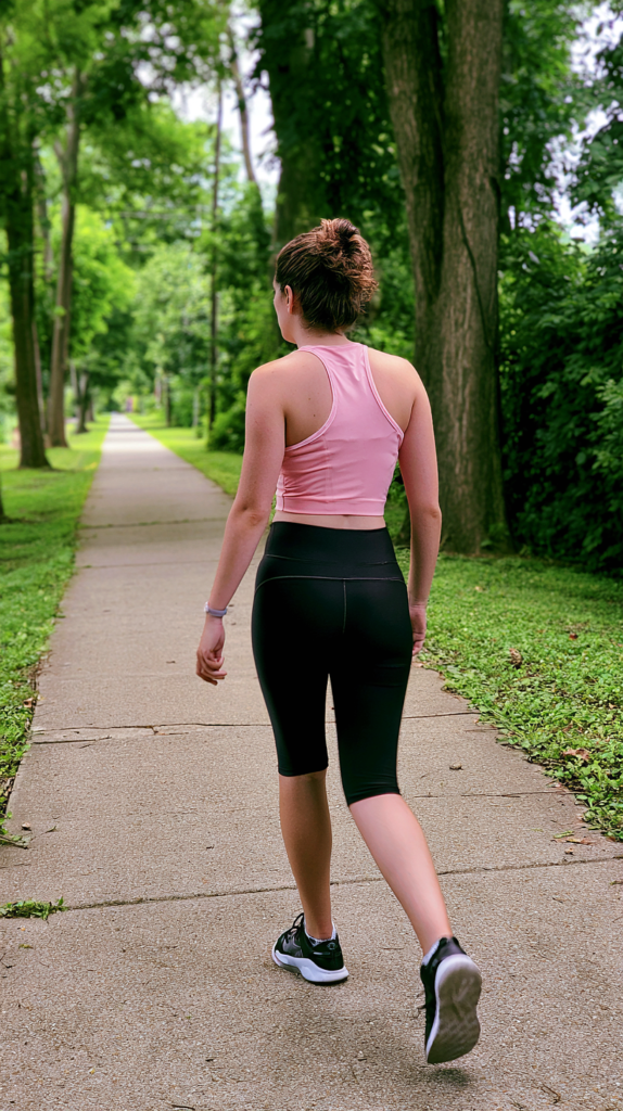 Pink crop tank and black capri leggings lightweight gym outfit on a tree-lined trail