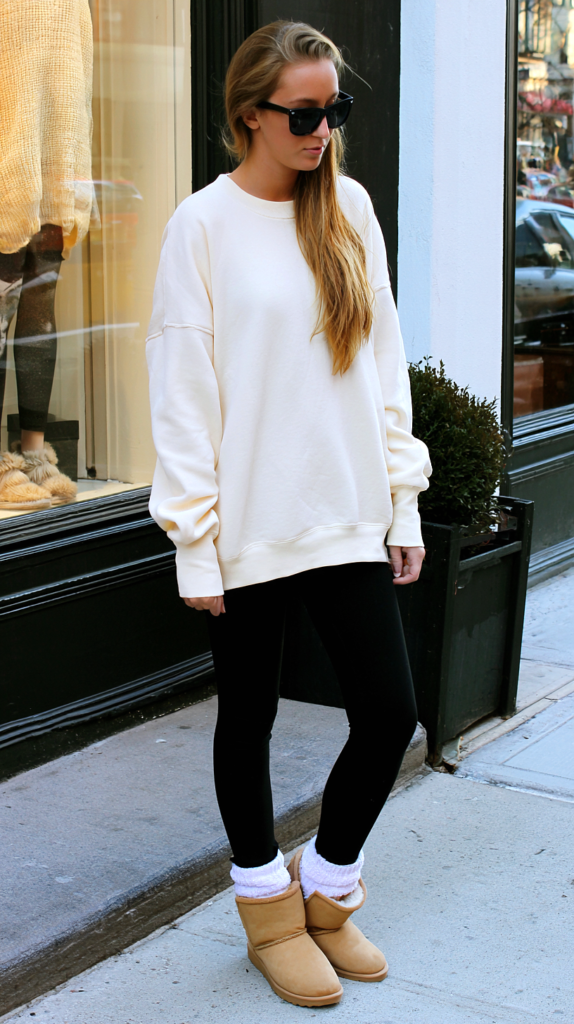 Cream sweatshirt and UGG boots yoga pants outfit with black leggings on a city sidewalk
